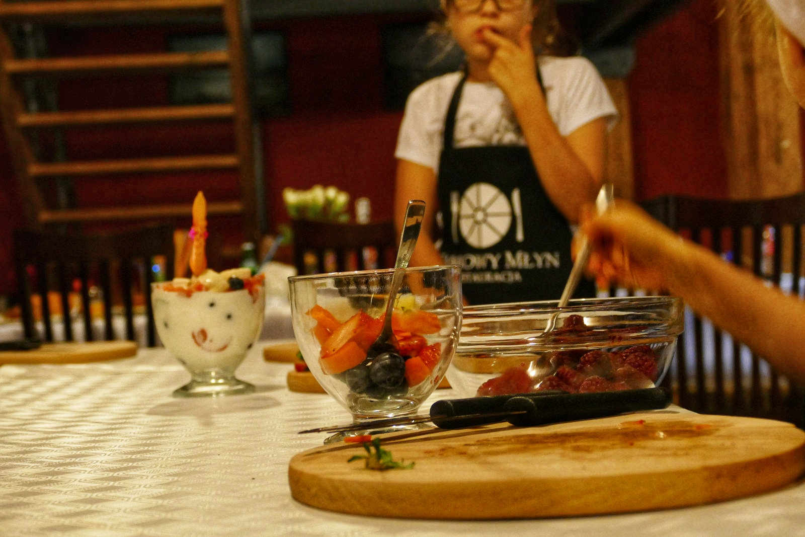 a woman in a black apron and a bowl of fruit